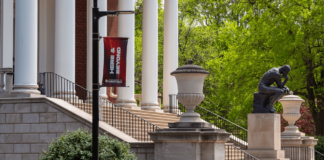 The Thinker Statue In the Springtime with a Here & Beyond Banner in the foreground