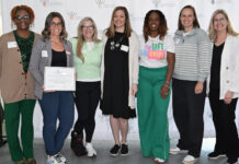 A group stands together holding an award.