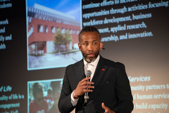 Man holding a microphone giving a talk.