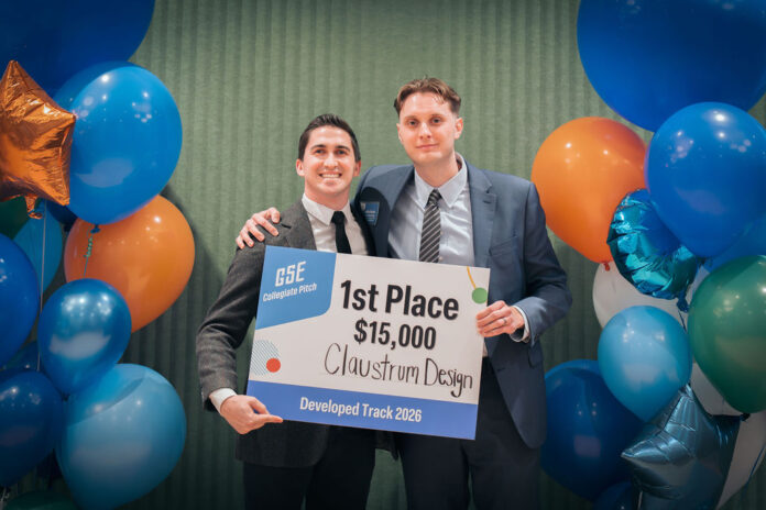Two male students hold a sign announcing their $15,000 win in a student competition