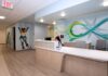 UofL, UofL Health and Kosair for Kids open expanded Pediatric NeuroRecovery Center Reception counter with colorful graphic murals, one includes a young child kicking a soccer ball