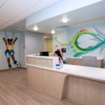 Reception counter with colorful graphic murals, one includes a young child kicking a soccer ball
