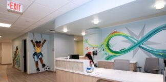 Reception counter with colorful graphic murals, one includes a young child kicking a soccer ball