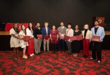 Students smile while holding awards and honors cords at a reception