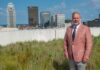 Man on grassy roof with Louisville, Ky. skyline in the background.