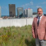 UofL launches Kentucky Center for Digital Innovation to advance research, education Man on grassy roof with Louisville, Ky. skyline in the background.