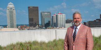 Man on grassy roof with Louisville, Ky. skyline in the background.