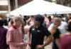 UofL President Bradley sets his goals for FY ’27 Two men talking with a large white tent and people walking in the background.
