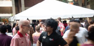 UofL President Bradley sets his goals for FY ’27 Two men talking with a large white tent and people walking in the background.