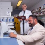 Two researchers in laboratory. One seated and the other standing.