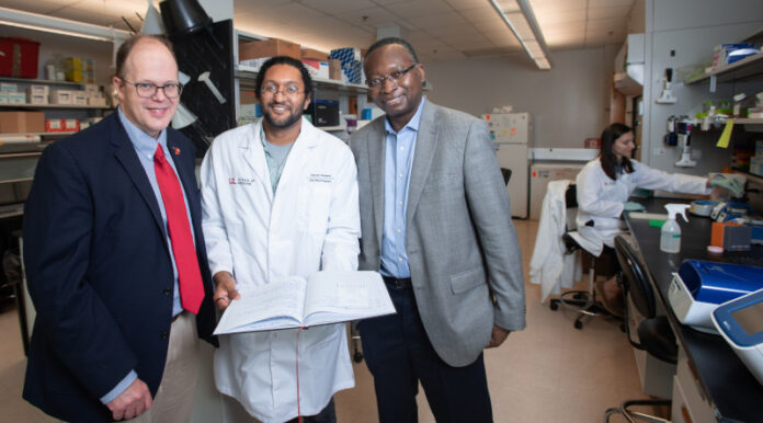 Three men standing in a medical research laboratory.
