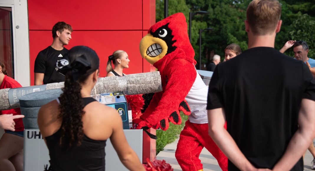 UofL welcomes Class of 2030 Louie the Cardinal bird mascot helps push items in a large bin into a residence hall.
