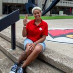 Why thousands of incoming students are saying #UofLYes Woman wearing red shirt sitting on the steps of the Health Sciences Center courtyard.