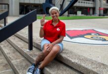 Woman wearing red shirt sitting on the steps of the Health Sciences Center courtyard.