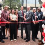 Members of the Louisville community cut a ribbon in front of the Bingham Humanities Building.