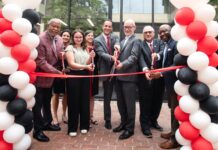 Members of the Louisville community cut a ribbon in front of the Bingham Humanities Building.