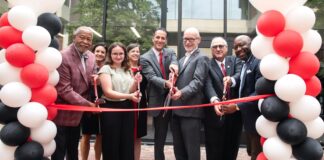 Members of the Louisville community cut a ribbon in front of the Bingham Humanities Building.