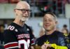 UofL recognized for outstanding support of military community Man in football jersey receives baton from Golden Knight