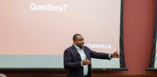 UofL leaders address compensation strategy at October town hall Darrell Clark speaks with his hands animated in front of a screen that states "Questions?"