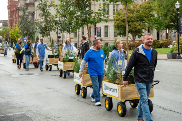 RH Moving Forest 16585 MED People pull wagons with trees and shrubs on the street.